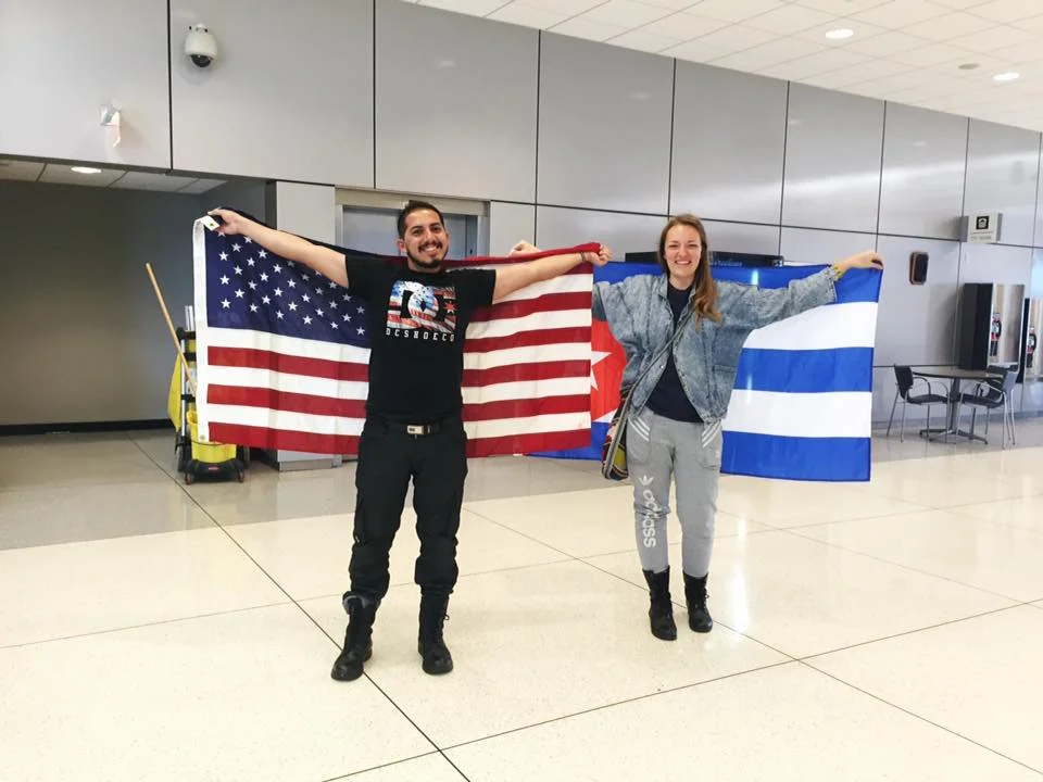 Carley and José holding US and Cuban flags.