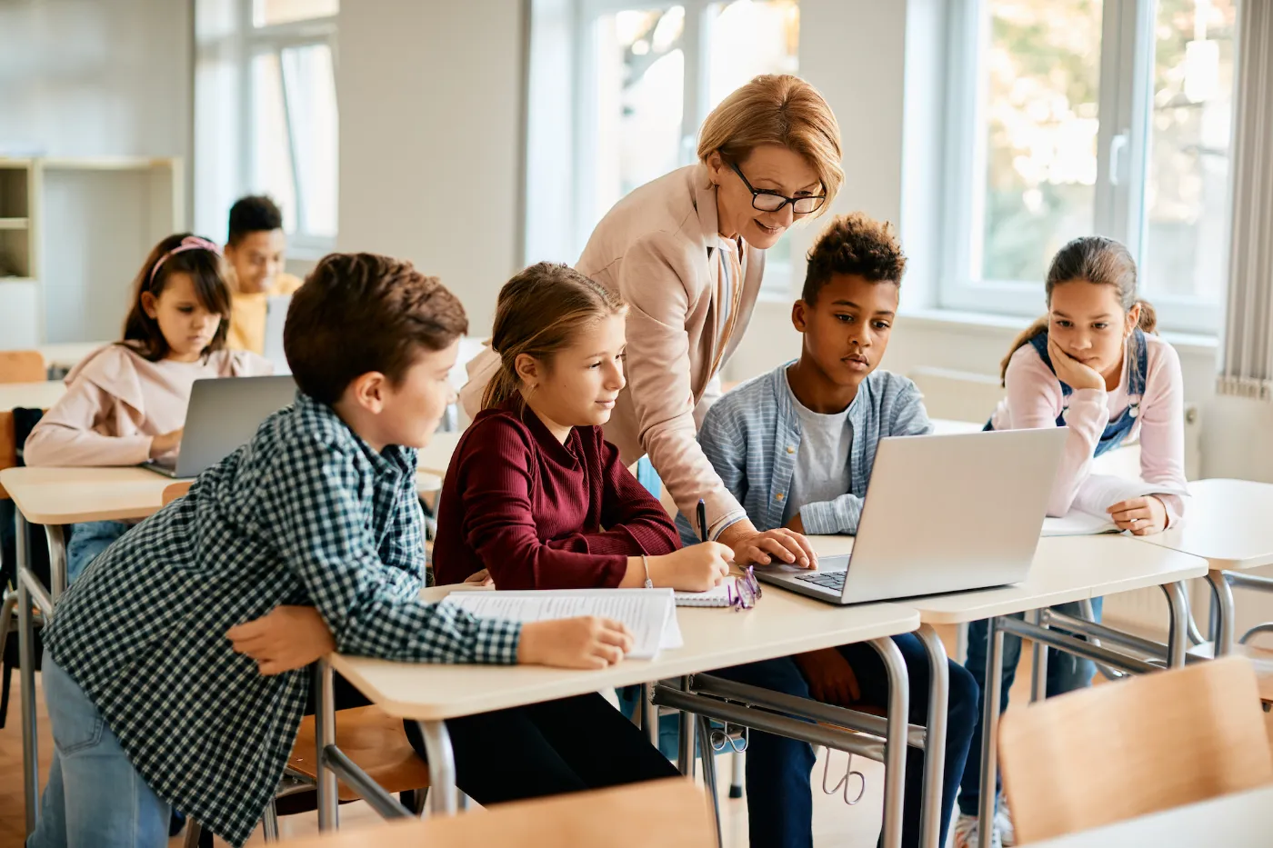 Stock image of teachers helping students on computer