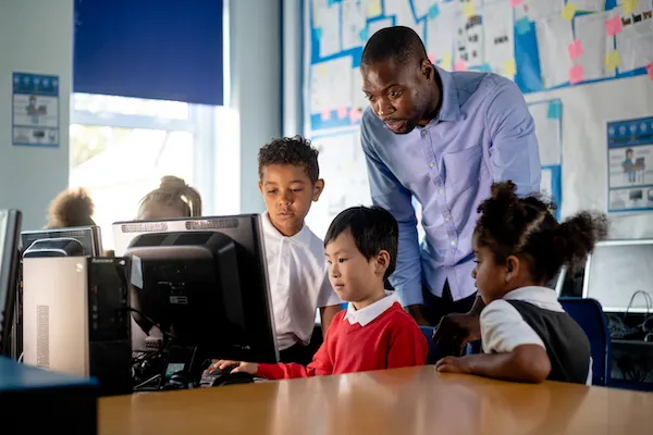 Another image of teachers helping students on computer.